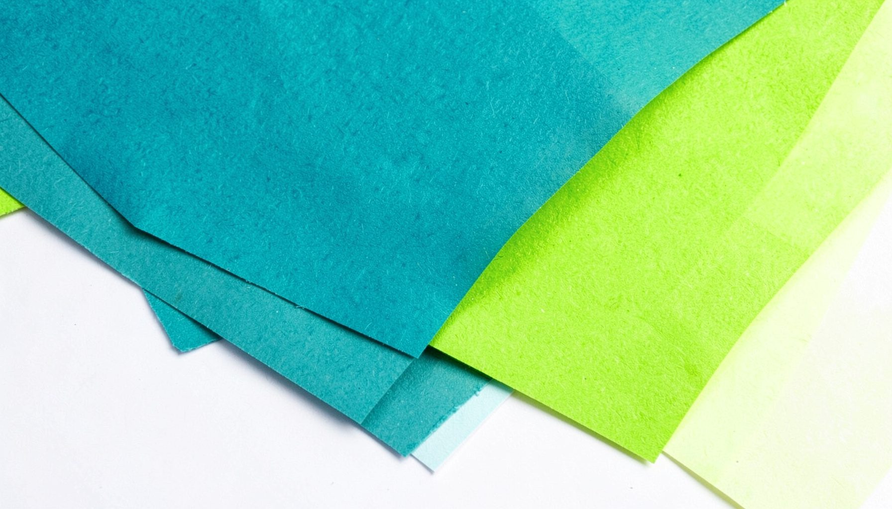 Abstract teal and lime paper textures layered on a clean white surface